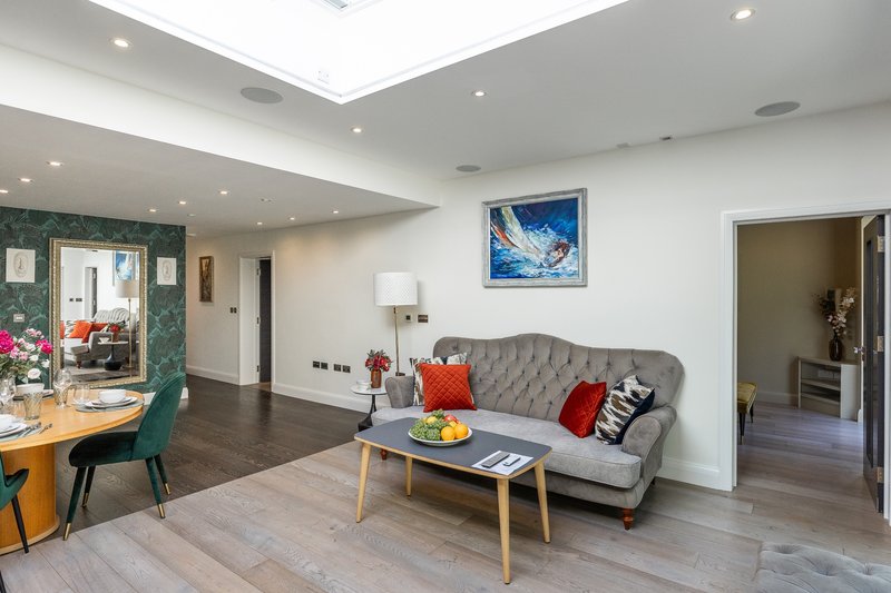 Modern open-plan living room with grey sofa, wooden coffee table, and dining area
