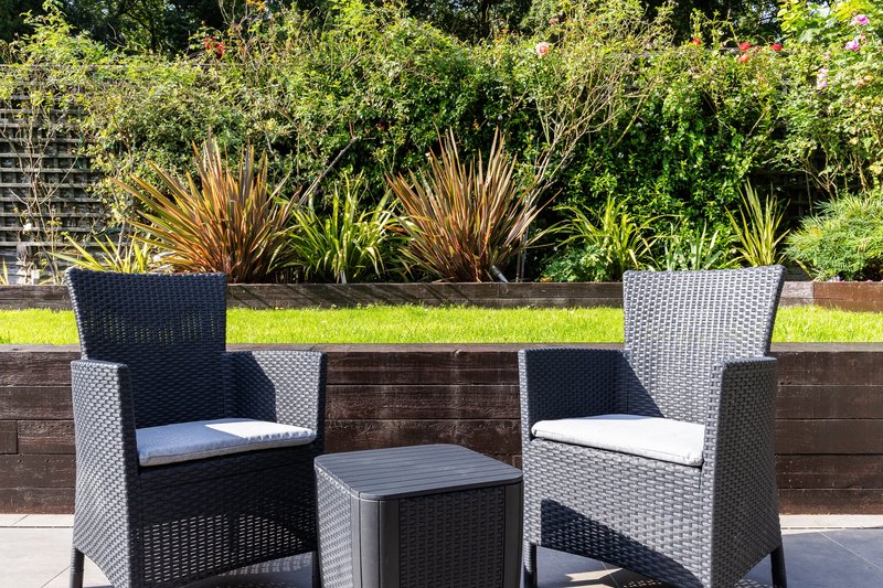 Garden patio seating area with rattan chairs, small table and potted plants