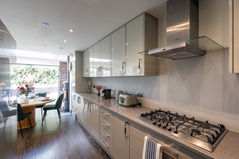 Modern galley kitchen with gas cooktop, built-in appliances, and dining area beyond