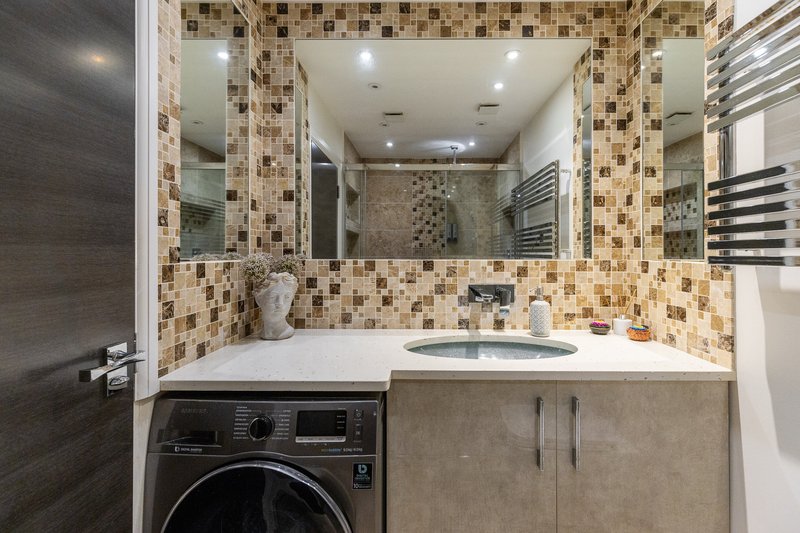 Modern bathroom with mosaic tile backsplash, integrated washing machine, vanity sink and large mirror