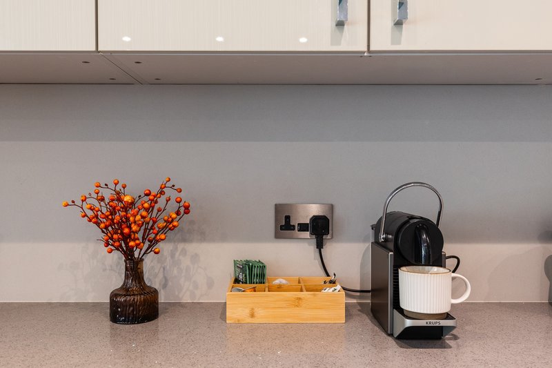 Modern kitchen counter with coffee machine, flower arrangement, and decorative items