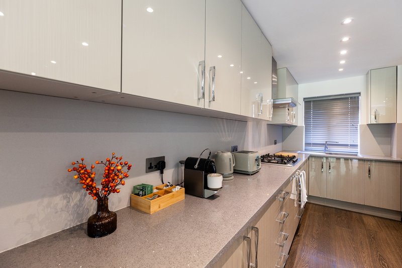 Modern kitchen with white cabinets, grey countertop, stainless steel appliances and decorative flowers