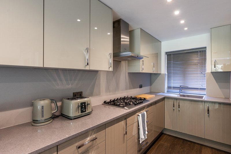 Modern kitchen with cream cabinets, gas hob, kettle, toaster and grey splashback