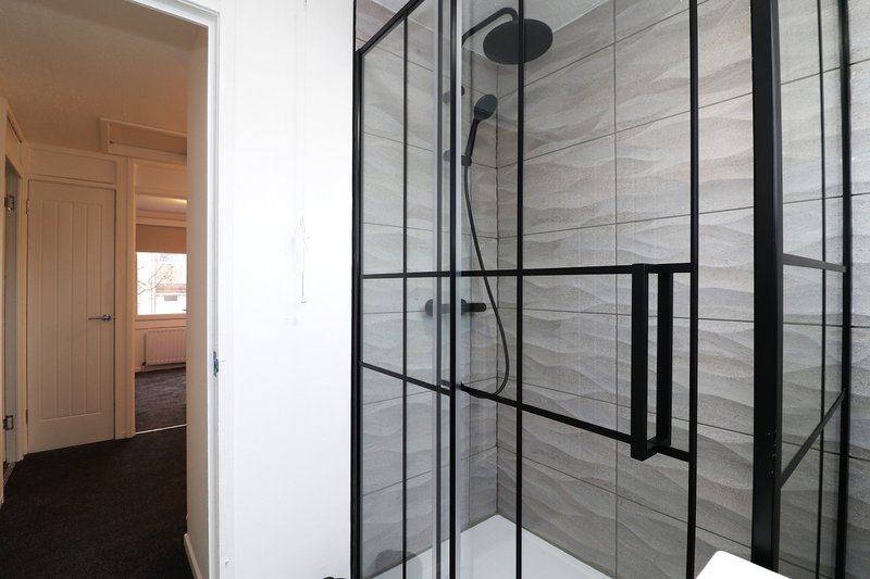 Modern bathroom with walk-in shower, black framed glass enclosure, gray tile walls