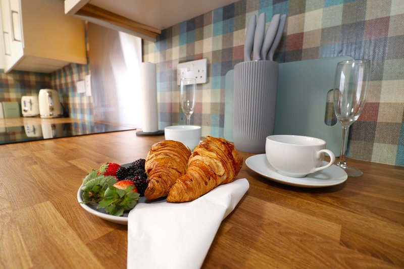 Kitchen counter with croissants, fresh fruit, coffee cup and utensil holder