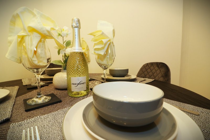 Elegant dining table setting with place settings, champagne bottle and glasses with yellow ribbon bows