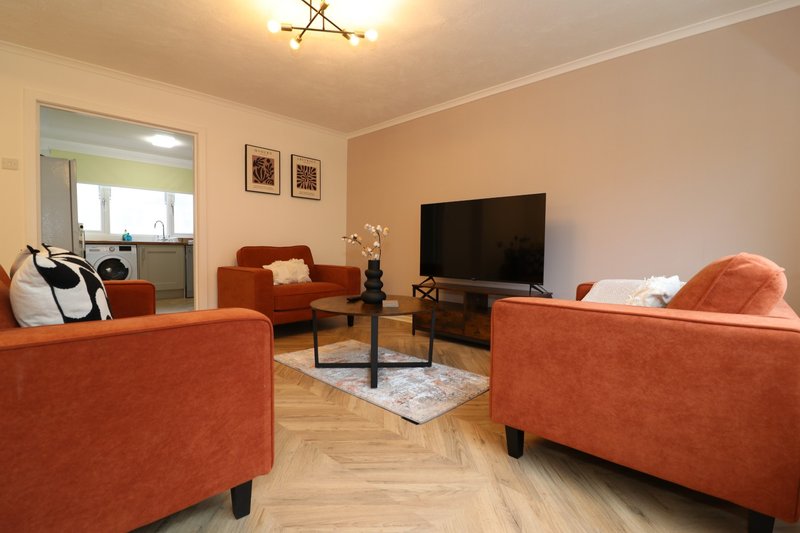 Spacious living room with orange sofas, TV, wooden floor and large mirror
