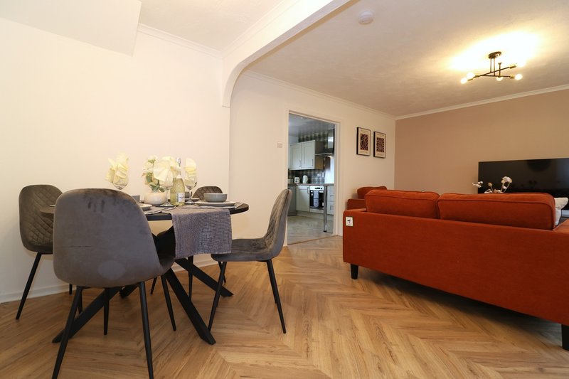 Open-plan living and dining area with red sofa, dining table, chairs and herringbone wooden flooring
