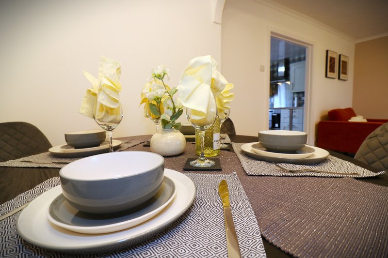 Dining table set with place settings, white bowls, and yellow flowers in vases