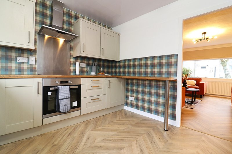 Modern kitchen with cream cabinets, blue checked backsplash, stainless steel appliances and wooden floor