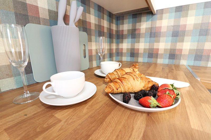 Dining table with breakfast spread including croissant, fresh berries, coffee cup and glasses