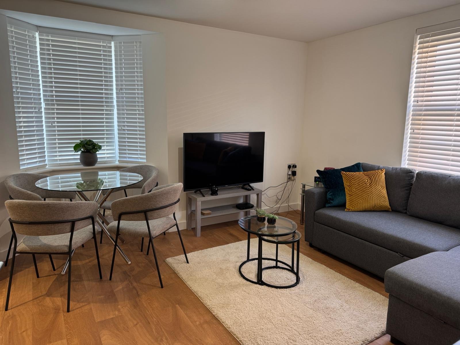 Modern living room with dining table, sofa, TV stand, and wooden flooring throughout
