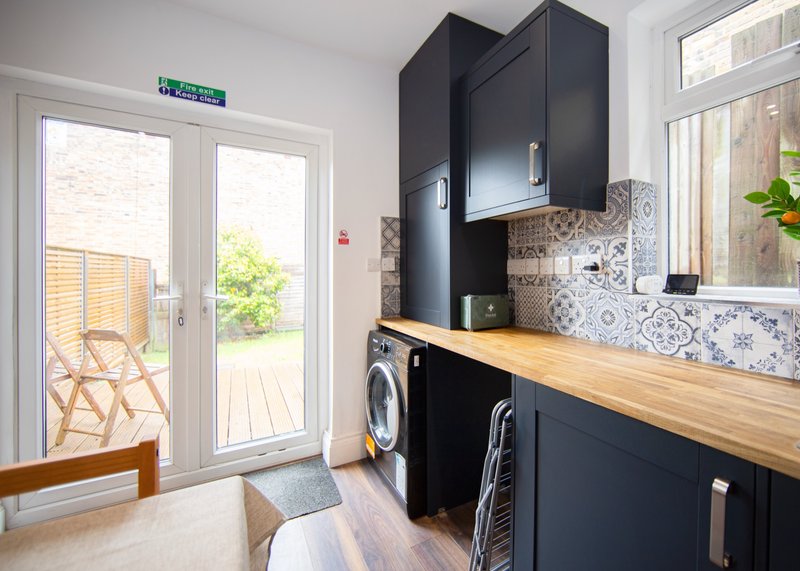 Modern kitchen with black cabinetry, wooden countertop, patterned backsplash and garden view