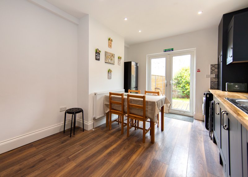 Kitchen-diner with wooden table, chairs, dark cabinetry, and garden access doors