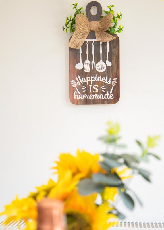 Kitchen wall decor with wooden sign and fresh yellow flowers in vase