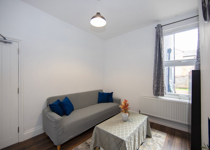 Bright living room with gray sofa, blue cushions, small table and window with curtains