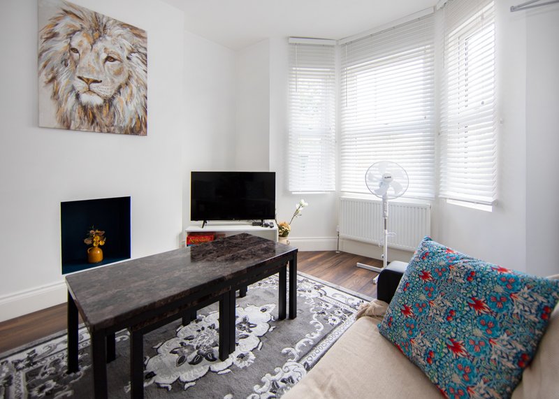 Living room with dark table, TV, fireplace, patterned sofa and lion artwork
