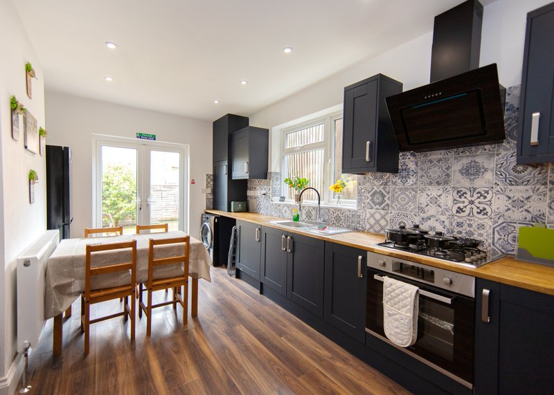 Modern kitchen with black cabinetry, patterned backtile, wooden worktops and dining area