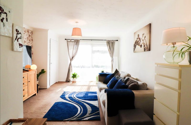 Modern living room with dark sofa, blue patterned rug, wooden furniture and large window
