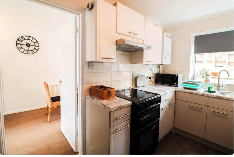 Compact kitchen with cream cabinets, black cooker, granite countertop and window overlooking garden