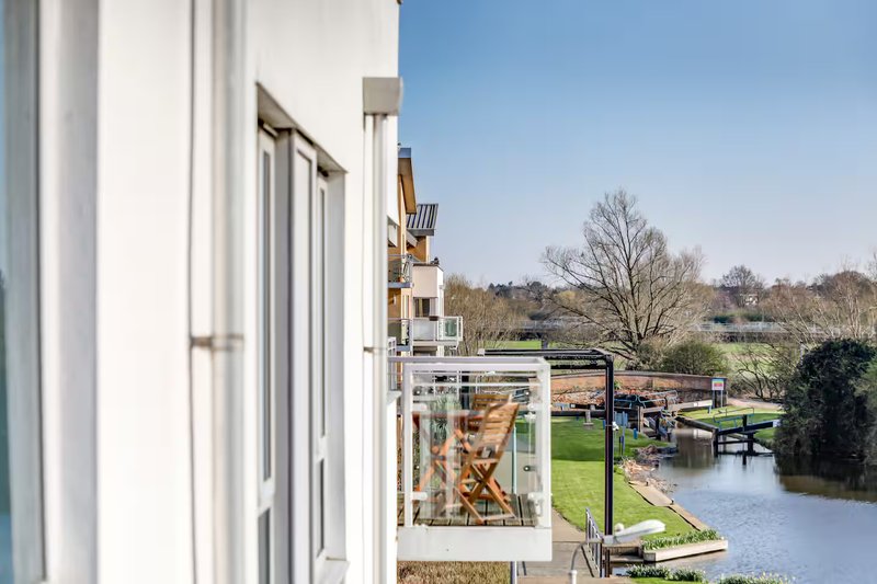 Modern white house exterior with glass doors overlooking garden, lawn and water feature
