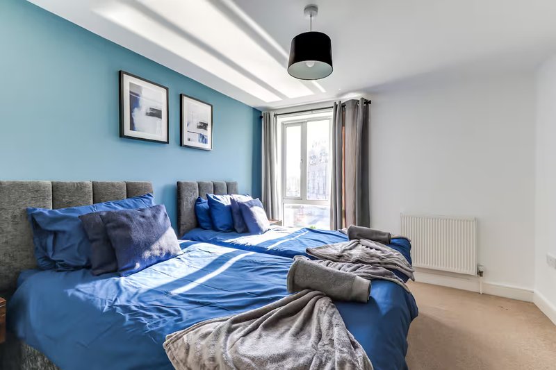 Bedroom with blue bed, grey headboard, wall art, pendant light and glass door