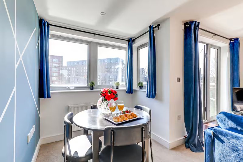Modern dining area with round table, flowers in vase, and city views through large windows