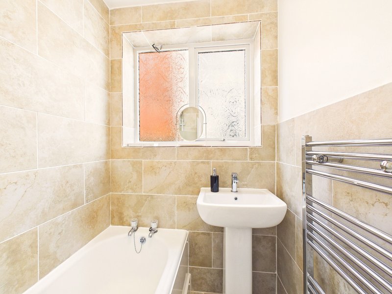 Bathroom with pedestal sink, bathtub, heated towel rail and window
