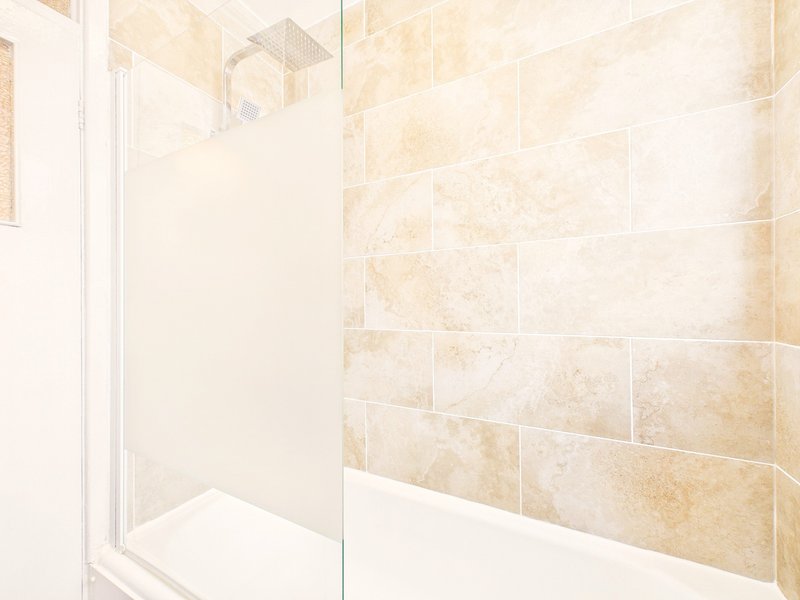 Modern bathroom with walk-in shower, cream and beige tile, glass enclosure
