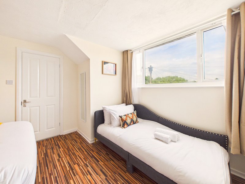 Bright bedroom with two single beds, wooden floor, window with countryside view