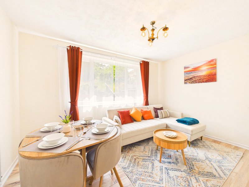 Open-plan living and dining area with sofa, dining table, cushions and wooden furniture