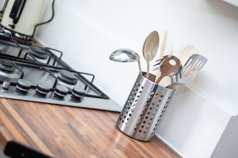 Kitchen counter with utensil holder containing cooking spoons and utensils next to stovetop
