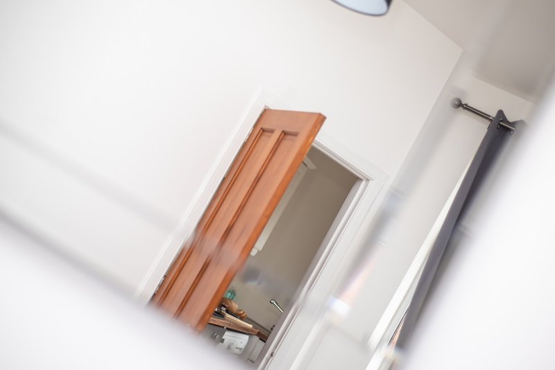 White ceiling with wooden beam, mirror, and metal rail fixture