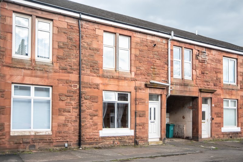 Red brick terraced house with multiple windows, white frames and recessed doorway entry