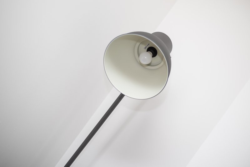 Modern floor lamp with white shade and black stem against white ceiling