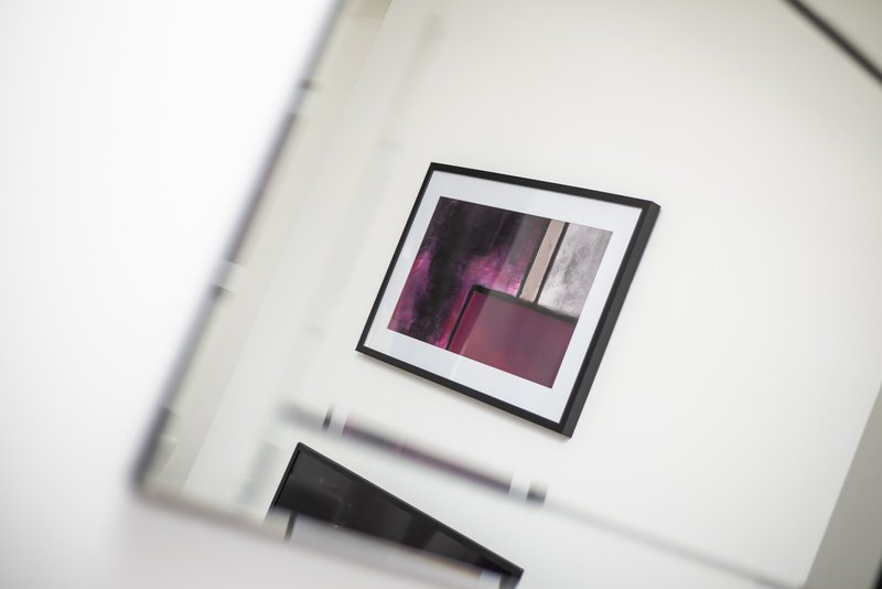White wall with framed abstract artwork in burgundy and grey tones