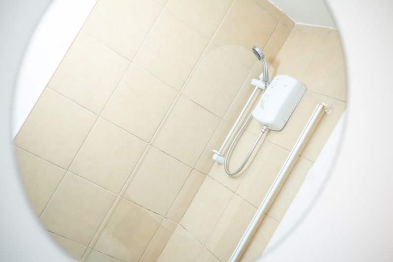 Bathroom shower enclosure with beige tile walls and chrome fixtures
