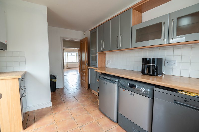Modern kitchen with grey cabinets, wooden countertops, stainless steel appliances and terracotta tiles