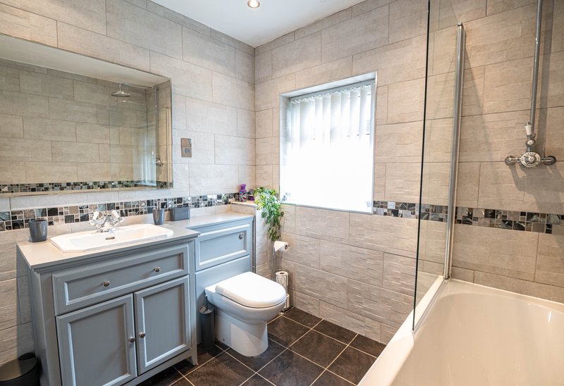 Modern bathroom with vanity unit, toilet, bath tub and walk-in shower enclosure