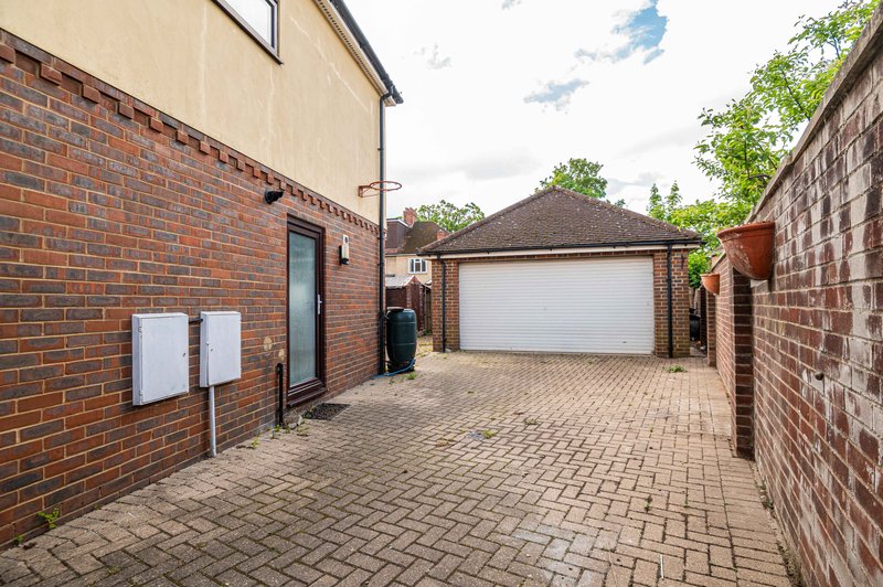 Brick driveway with garage, side entrance door, and surrounding brick walls