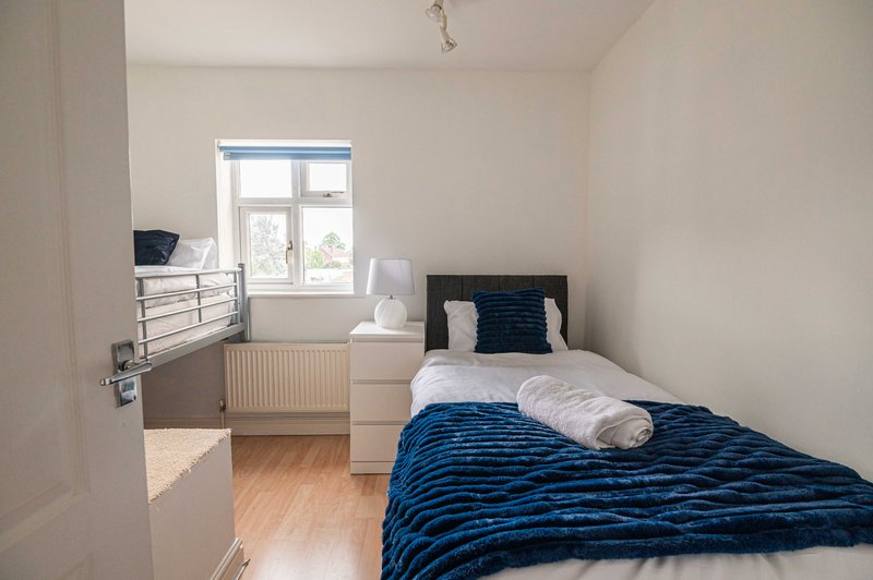 Bright bedroom with single bed, blue bedding, wooden floor and window with natural light