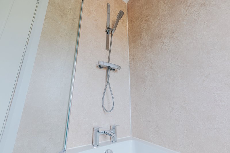 Modern bathroom shower enclosure with chrome fixtures and beige tiled walls
