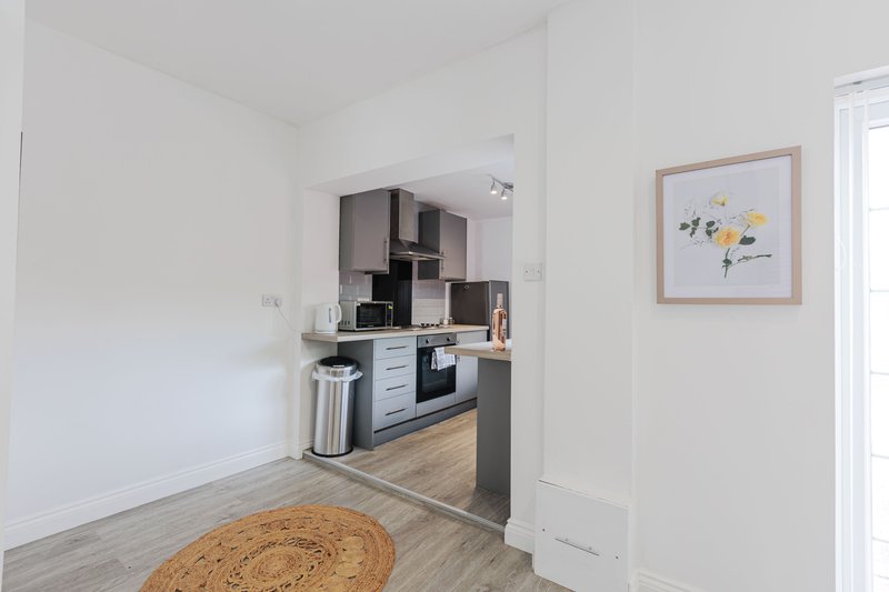 Open-plan kitchen and living area with modern fitted kitchen, wooden flooring, and wall art