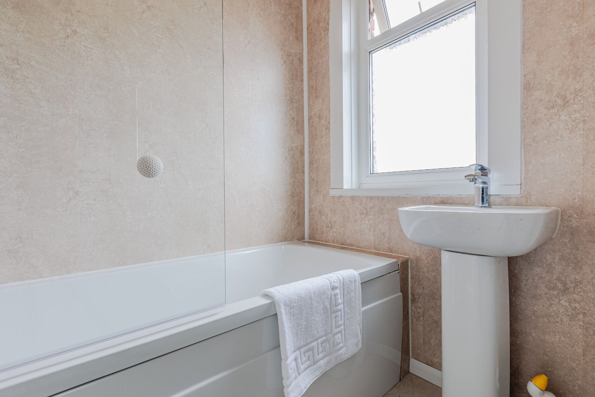 Modern bathroom with bathtub, pedestal sink, window and tiled walls