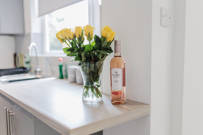 Modern kitchen counter with yellow flowers in vase and wine bottle