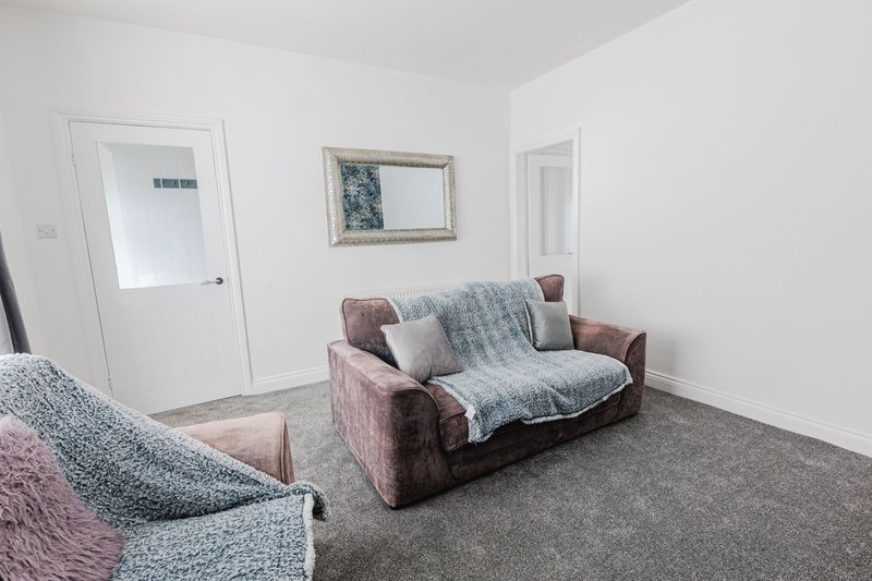 Living room with two upholstered sofas, throw blankets, mirror and white doors