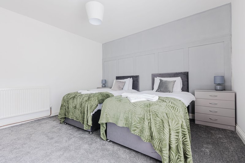 Modern bedroom with twin beds, green quilts, built-in wardrobes and bedside tables