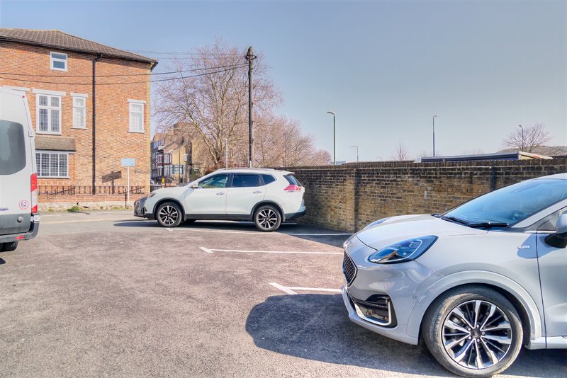 Brick building exterior with parking area, parked cars, and stone wall