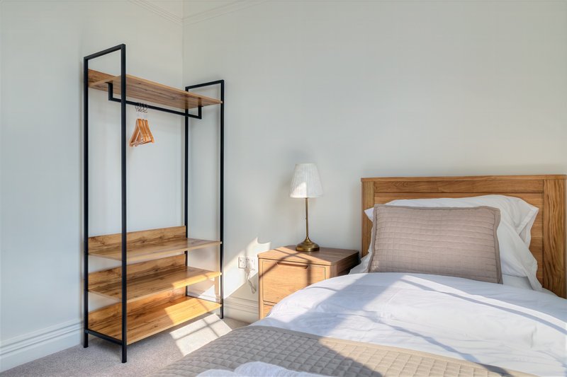 Bedroom with double bed, wooden wardrobe rack, bedside lamp and nightstand