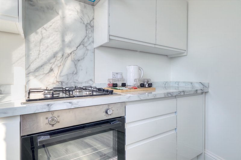 Modern white kitchen with marble backsplash, gas hob, built-in oven and countertop appliances